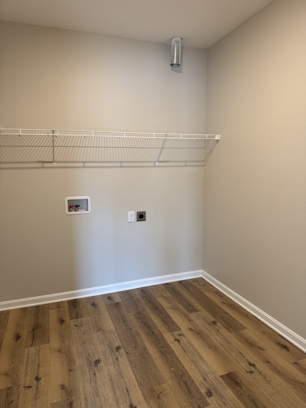 A room with a white wall and a shelf on the wall.