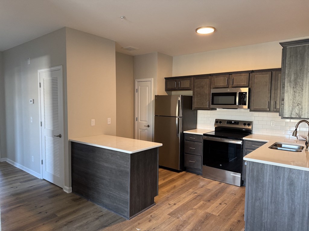 A kitchen with a refrigerator, oven, and microwave.