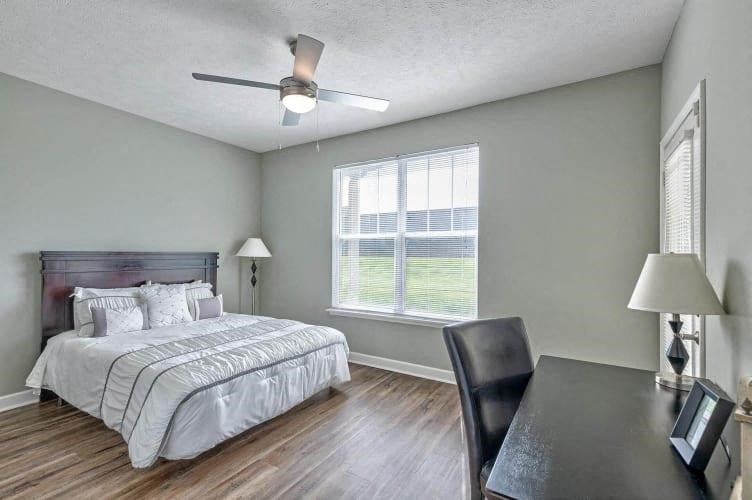 a bedroom with a bed and a desk and a ceiling fan