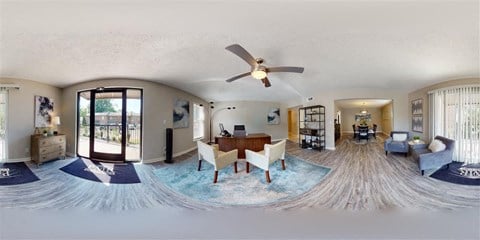 a living room with a table and a ceiling fan