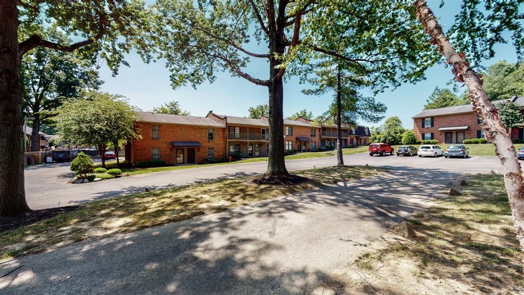 the street in front of a brick apartment building with trees