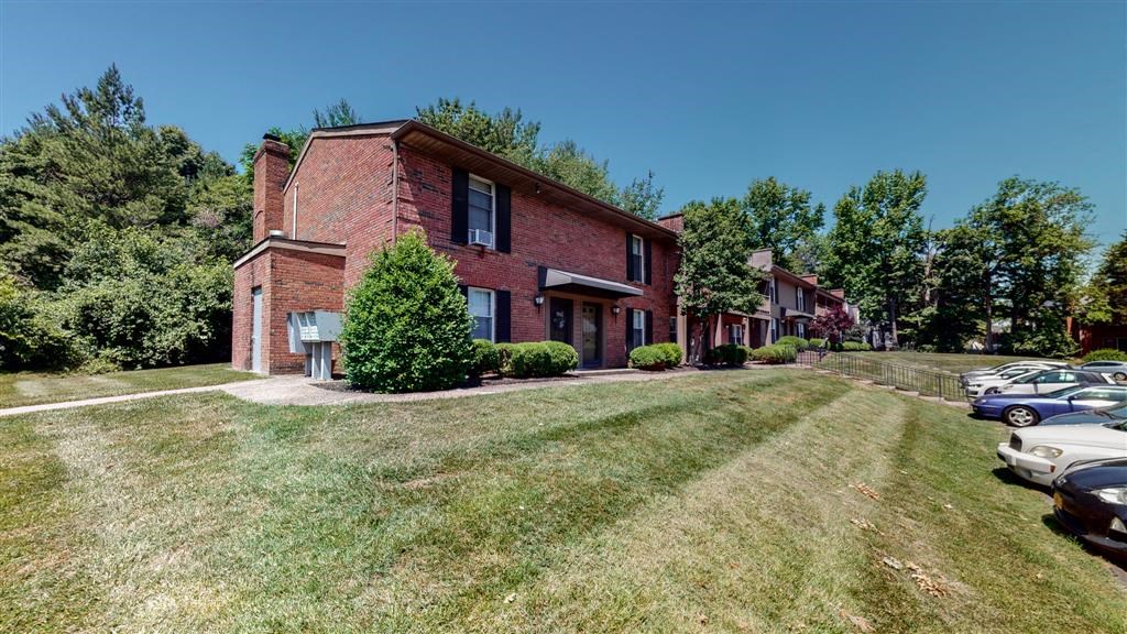 a red brick house with cars parked in front of it