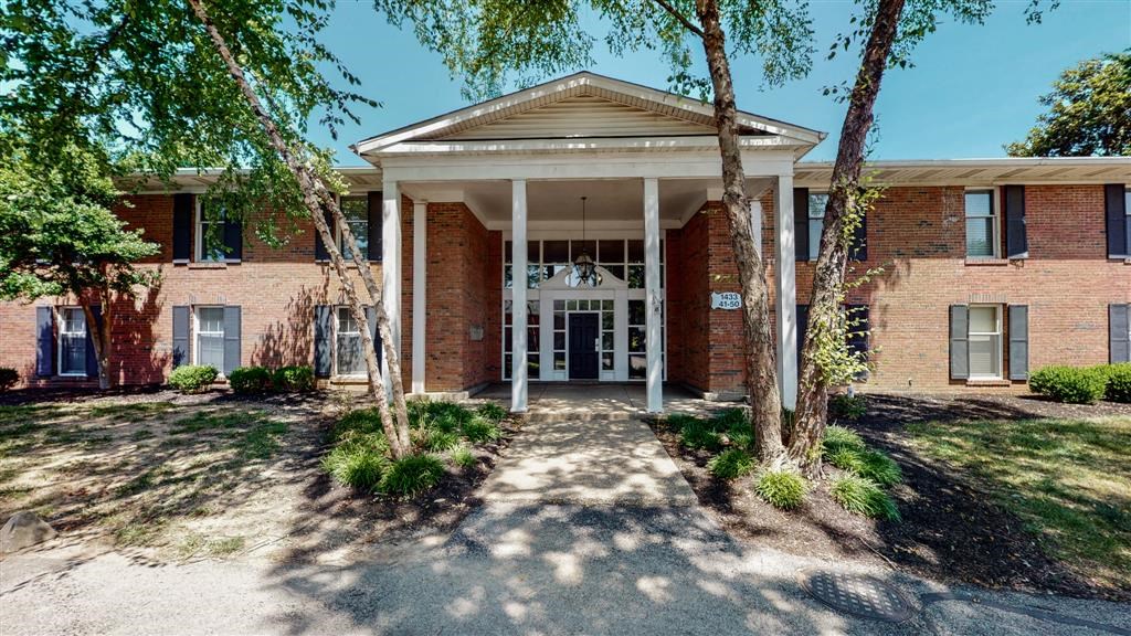 the front entrance of a brick building with trees