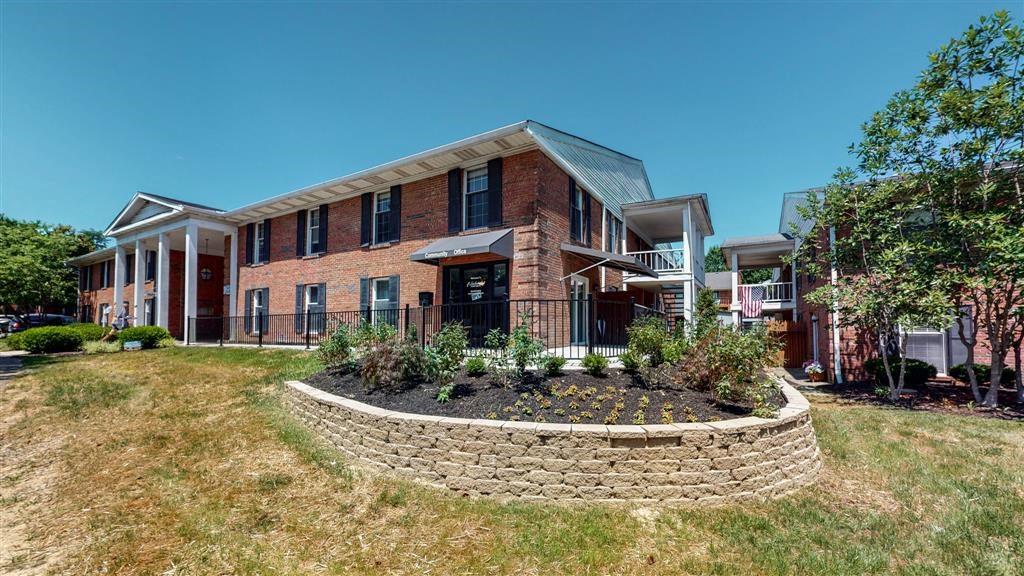 the front of a brick building with a retaining wall
