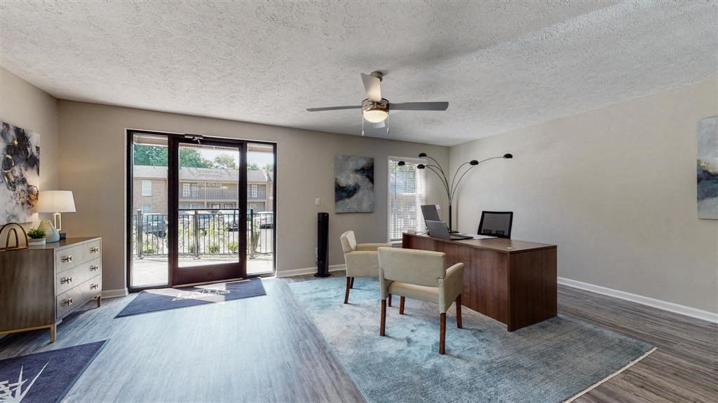 a living room with a desk and a sliding glass door