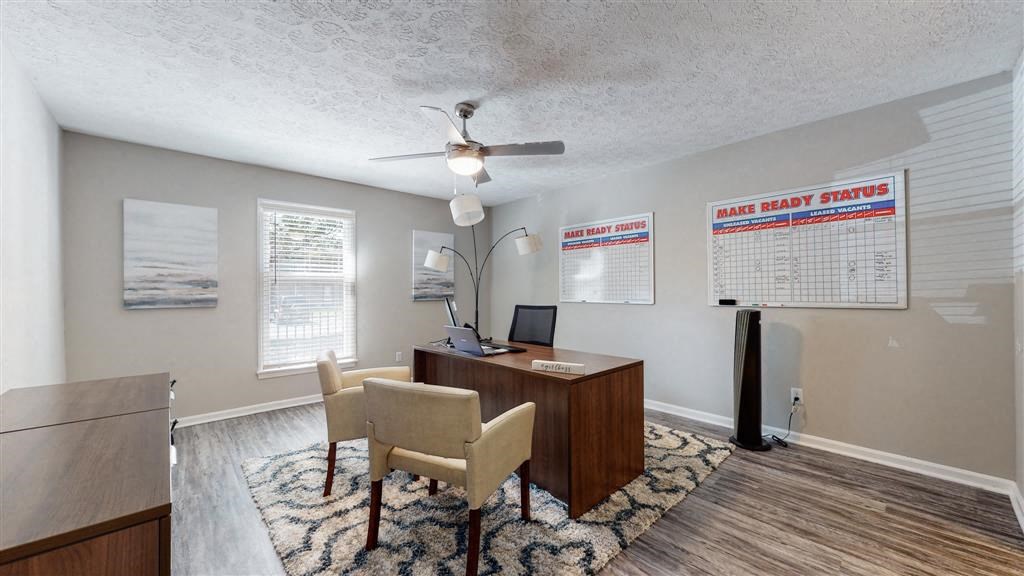 a living room with a desk and chairs and a ceiling fan