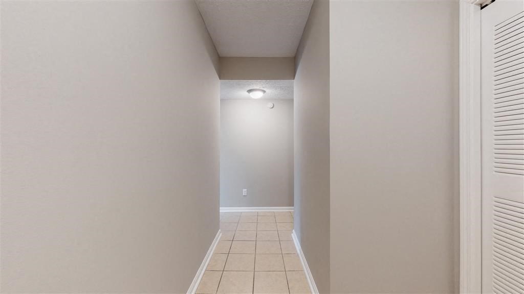 a hallway with white walls and a tile floor