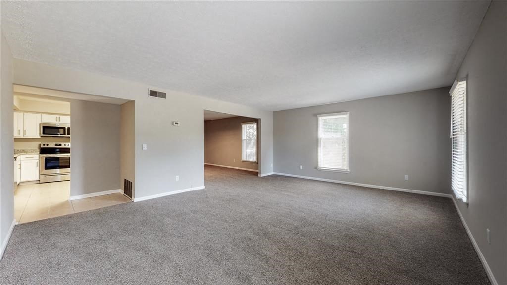 an empty living room with a kitchen in it