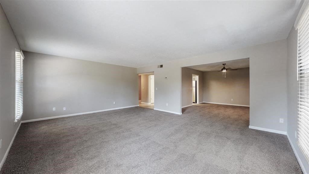 an empty living room with a white ceiling and carpet