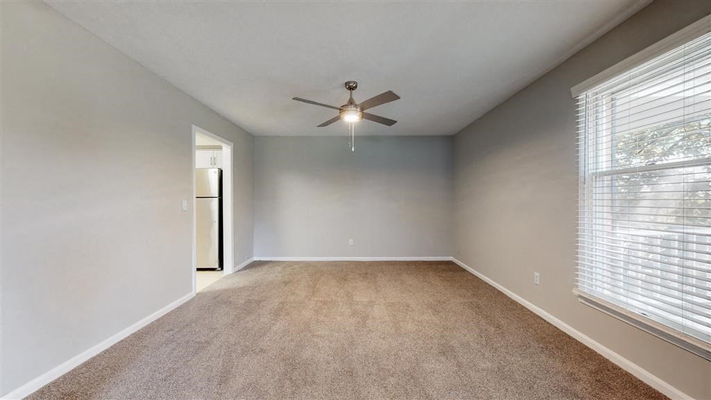 an empty living room with a ceiling fan and a large window