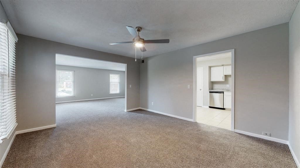 an empty living room with a ceiling fan