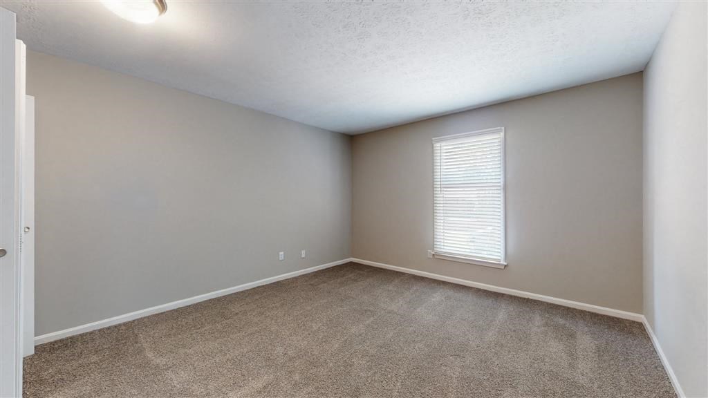 an empty living room with a large window and carpet
