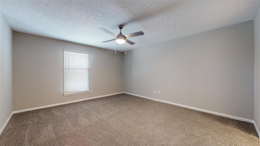an empty room with a ceiling fan and a window
