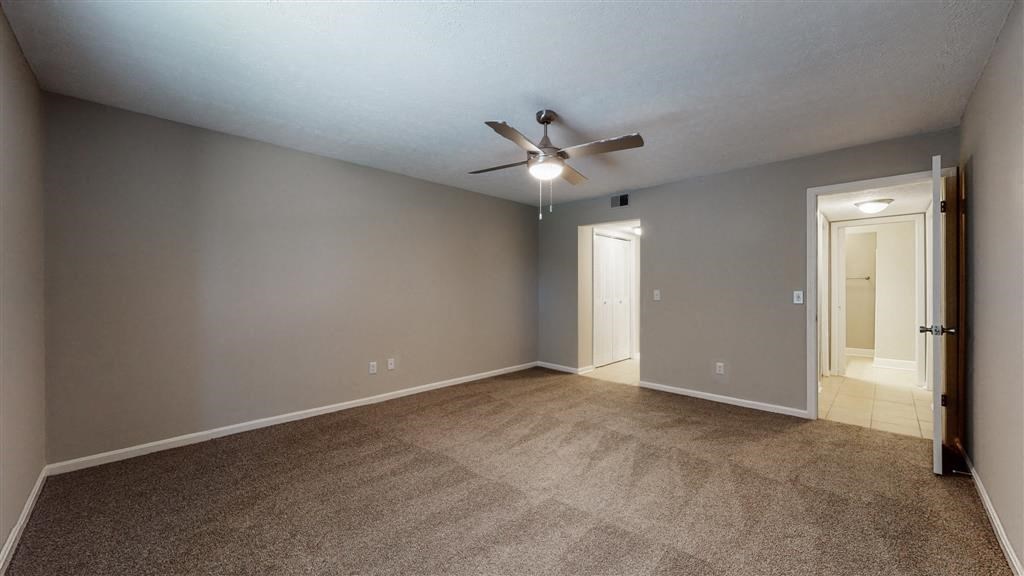 an empty living room with a ceiling fan