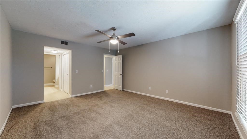 an empty living room with a ceiling fan