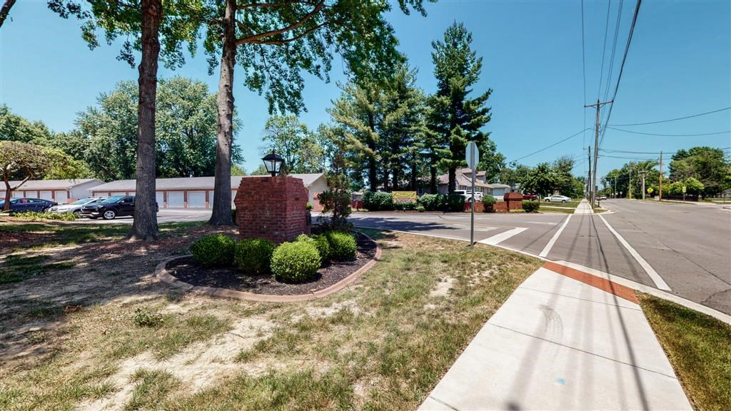 a street corner with a brick monument and trees
