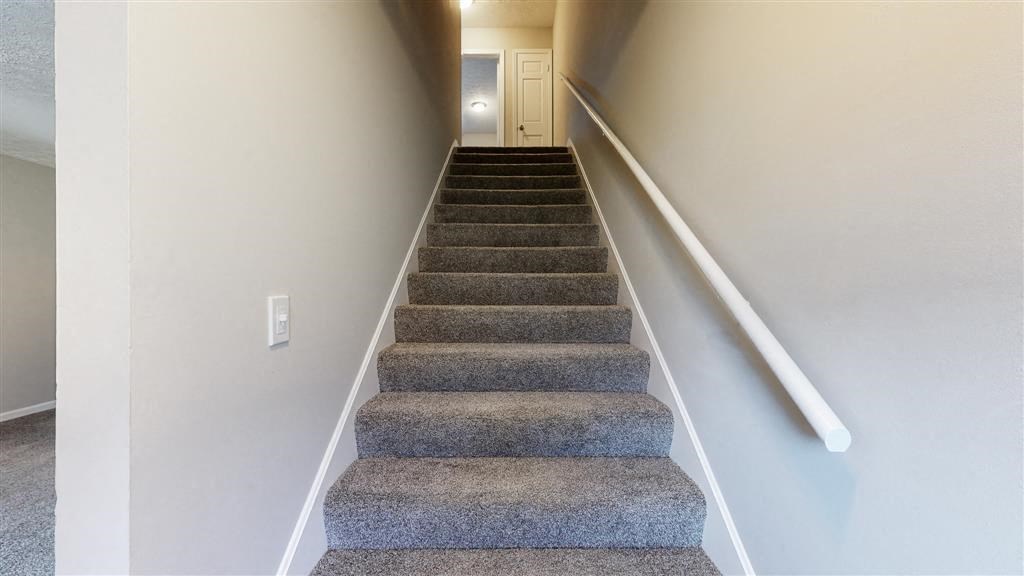 a staircase with carpeted stairs and a white railing