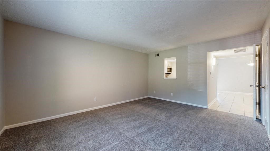 an empty living room with a door to a bathroom