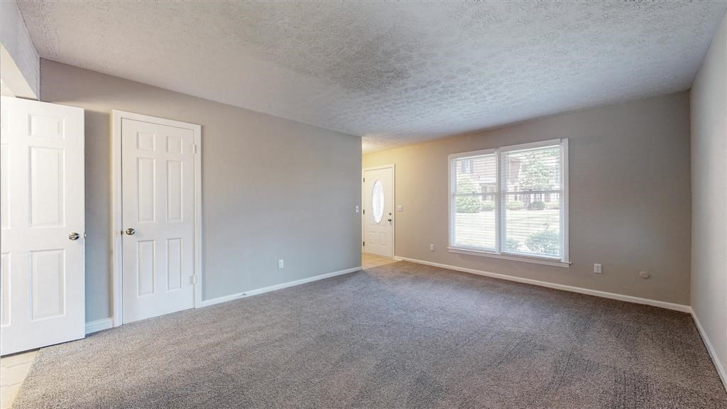 an empty living room with a window and a door