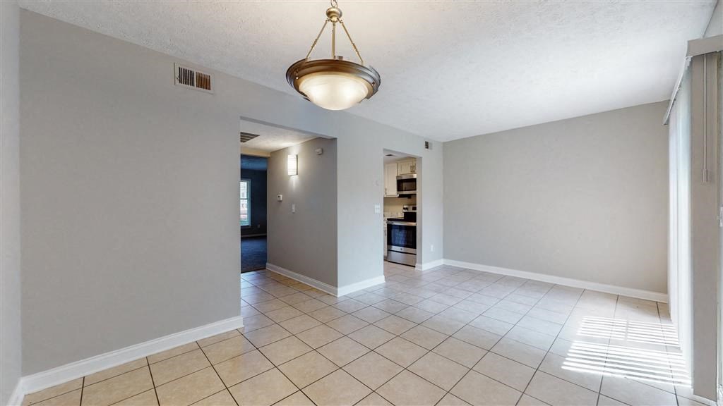 an empty living room with a light hanging from the ceiling