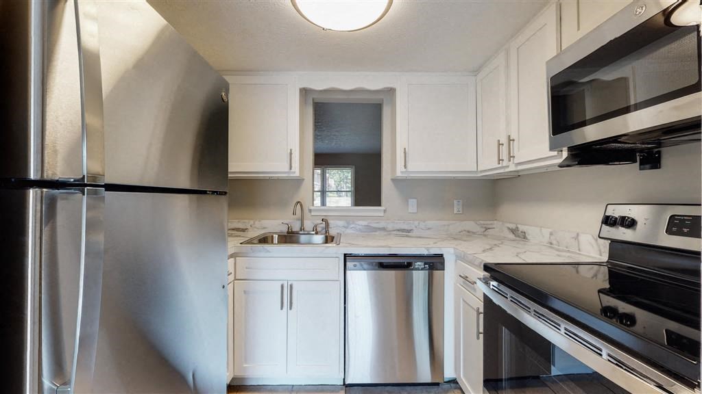 a kitchen with white cabinets and a stainless steel refrigerator