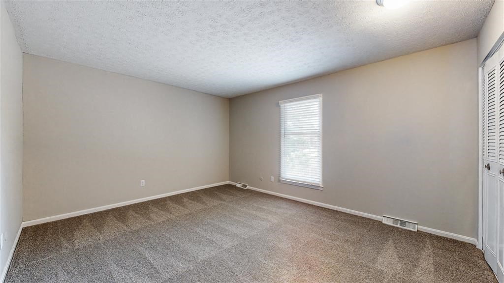 an empty bedroom with a large window and carpeting