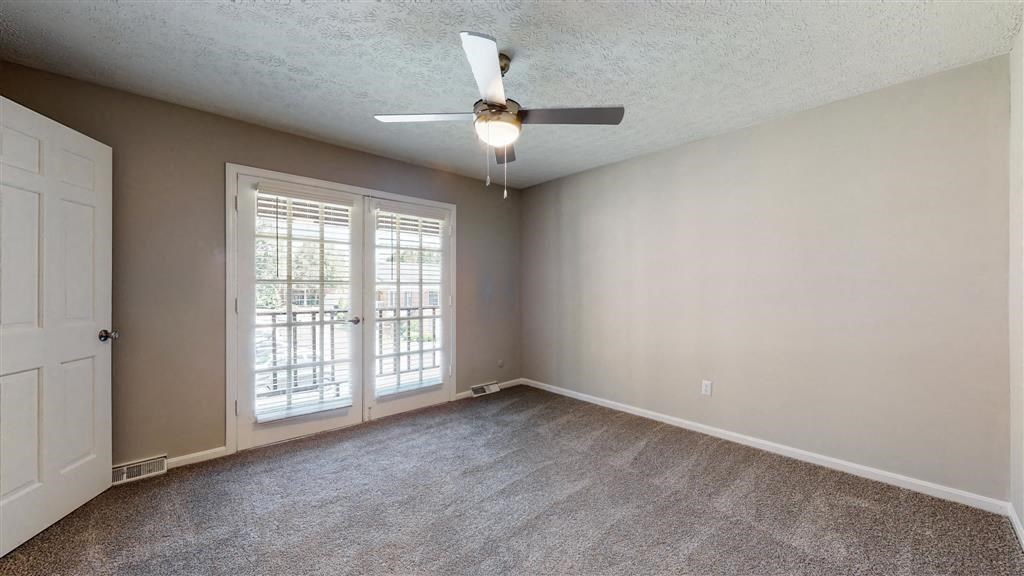 an empty living room with a ceiling fan and a door