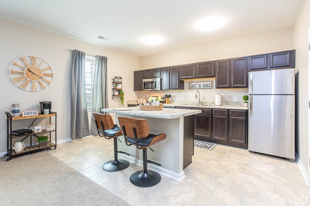 a kitchen with a bar and a stainless steel refrigerator