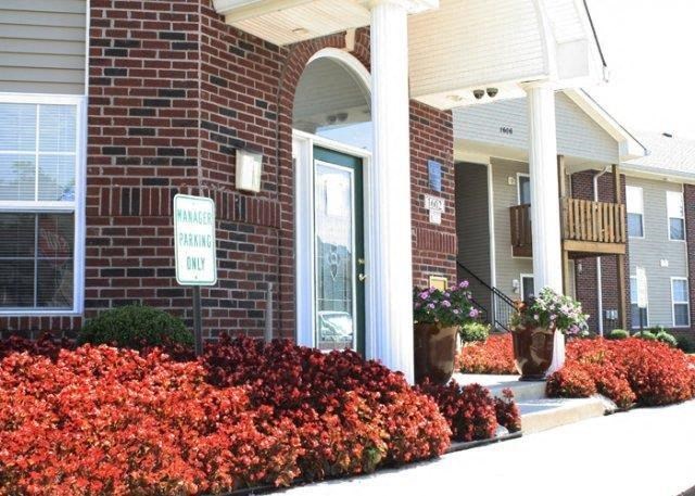a front porch of a brick house with red flowers