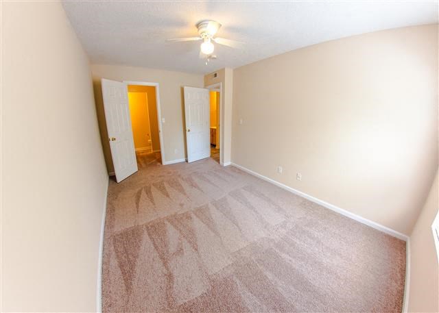 a empty room with a carpeted floor and a ceiling fan