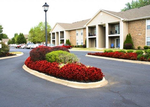 a roundabout in the middle of a street with flowers and bushes