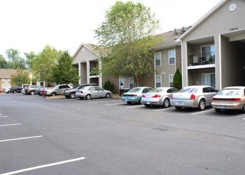 a parking lot with cars parked in front of apartment buildings