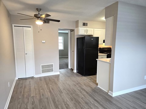 A black refrigerator in a kitchen with white walls and wood flooring.