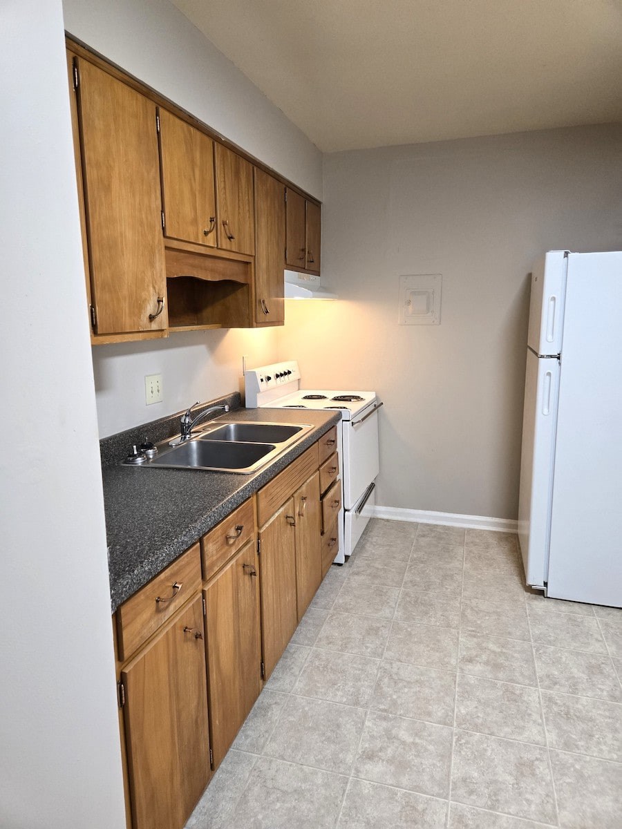 A kitchen with wooden cabinets and a white refrigerator.