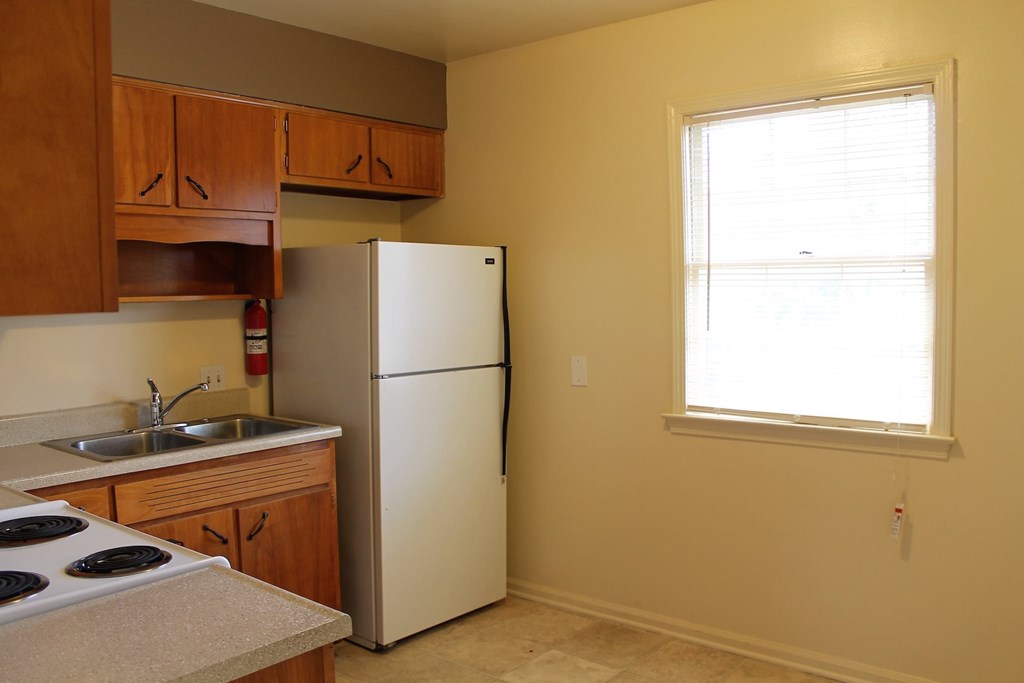 A kitchen with a white refrigerator and wooden cabinets.