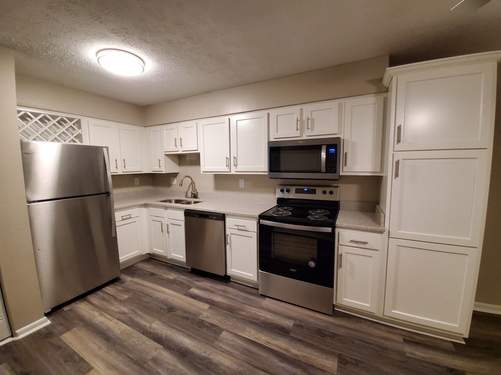 A kitchen with white cabinets and a wood floor.