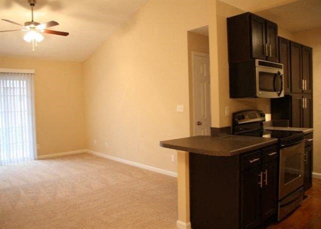 a living room with a kitchen with a stove and microwave