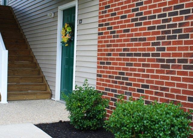 a brick building with a green door and some bushes