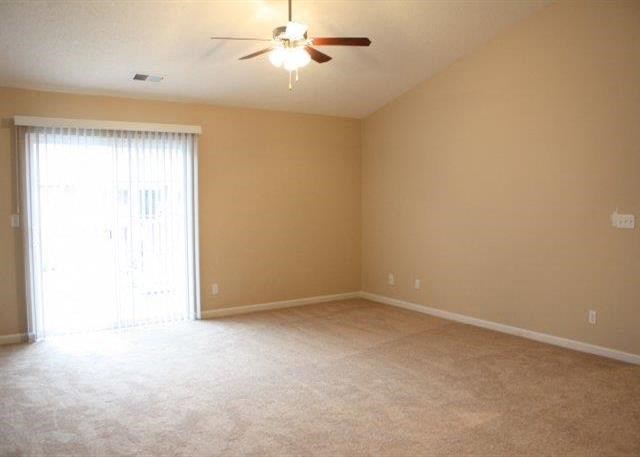 an empty living room with a ceiling fan and a window