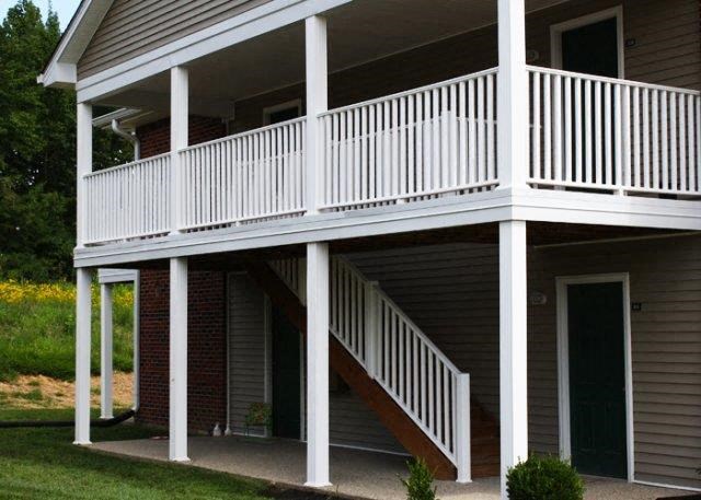 a white porch with a white railing on a house