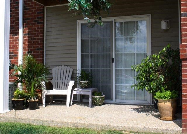 a porch with two chairs and potted plants and a door