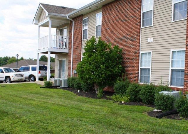a brick house with a balcony and a yard