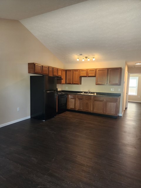 A kitchen with wooden cabinets and a black refrigerator.