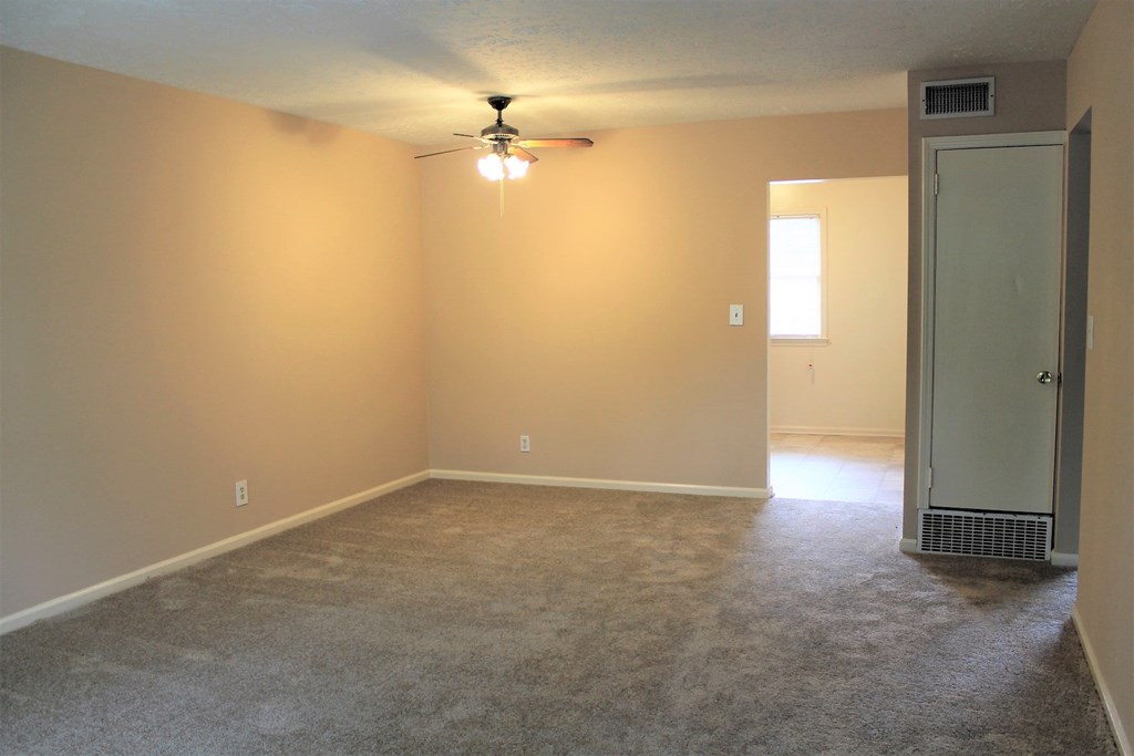 A room with a carpeted floor and a ceiling fan.