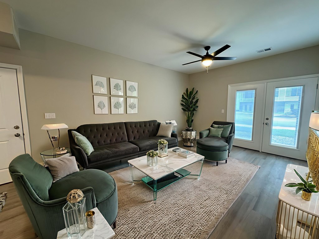A living room with a black sofa, green armchair, and a glass coffee table.