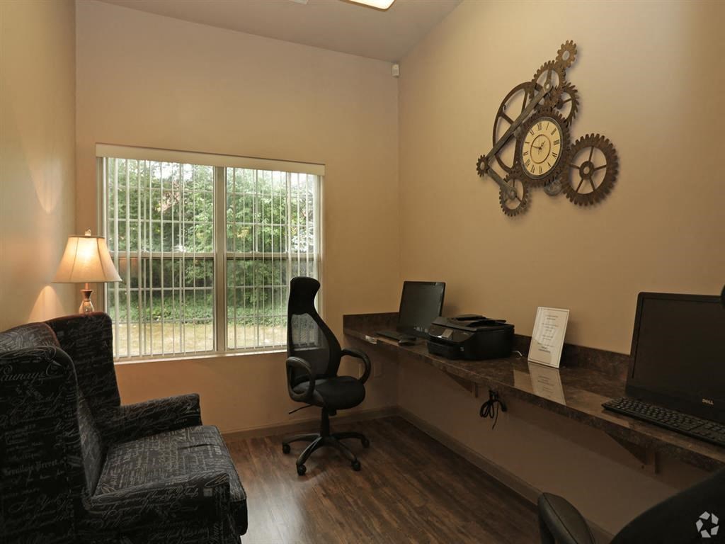 an office with a desk with a computer and a clock on the wall