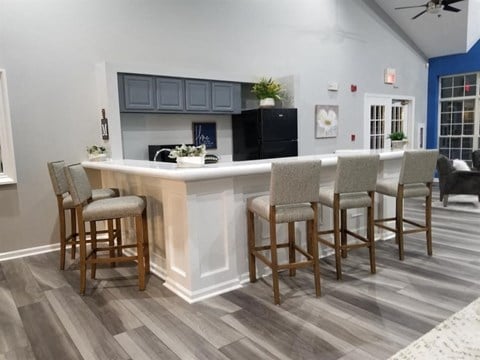 a kitchen with a bar and chairs in a living room