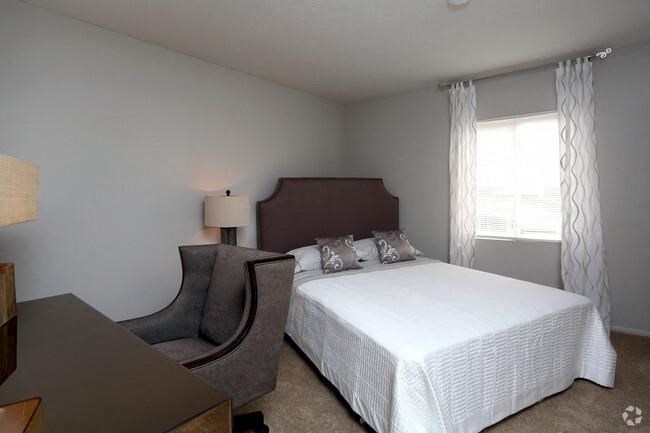 a bedroom with a large bed and a chair