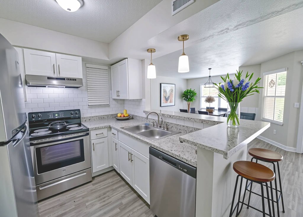 A kitchen with a stove, oven, and bar stools.