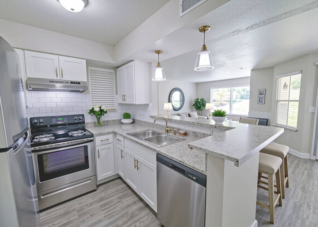 A modern kitchen with a stainless steel refrigerator, a stove, and a marble countertop.
